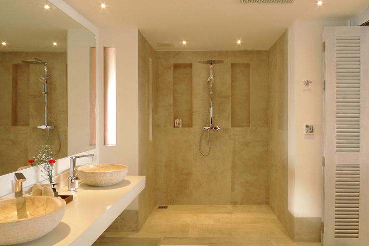 The large luxury bathroom of bedroom suite 3, finished in cooling floor-to-ceiling marble, leading to the outdoor garden bathroom with a sunken bath tub and a second shower.