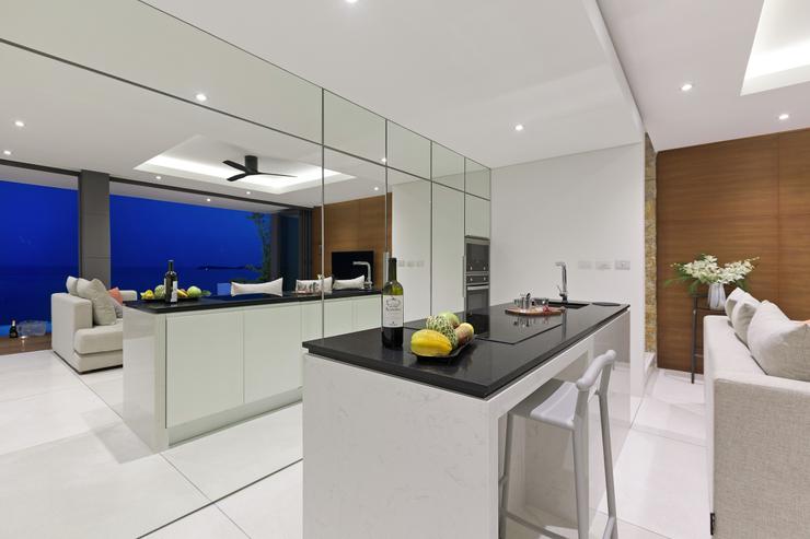 Villa Channary -  A modern kitchen designed around a white marble island counter with its tall cabinets hidden behind mirrors